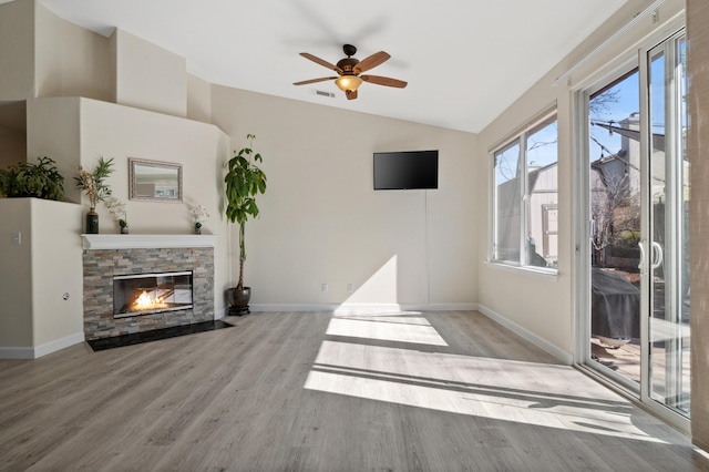 living area featuring wood finished floors, a fireplace, baseboards, and lofted ceiling