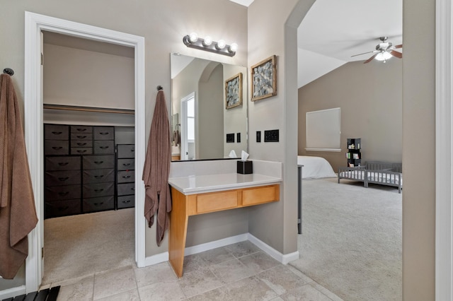 bathroom with lofted ceiling, a ceiling fan, ensuite bath, baseboards, and vanity