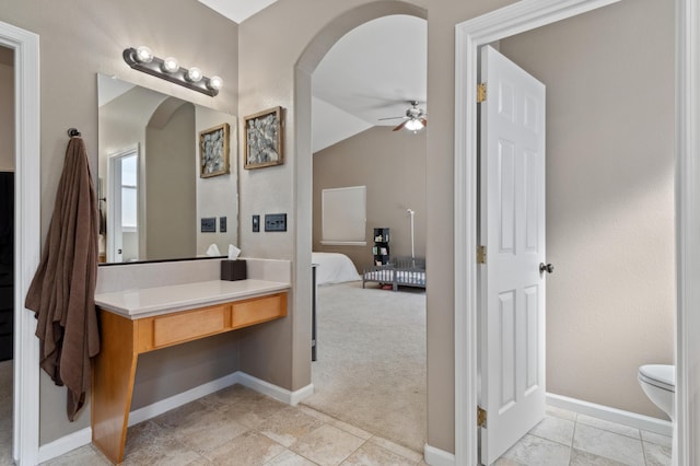 ensuite bathroom featuring baseboards, toilet, vaulted ceiling, ensuite bath, and a ceiling fan