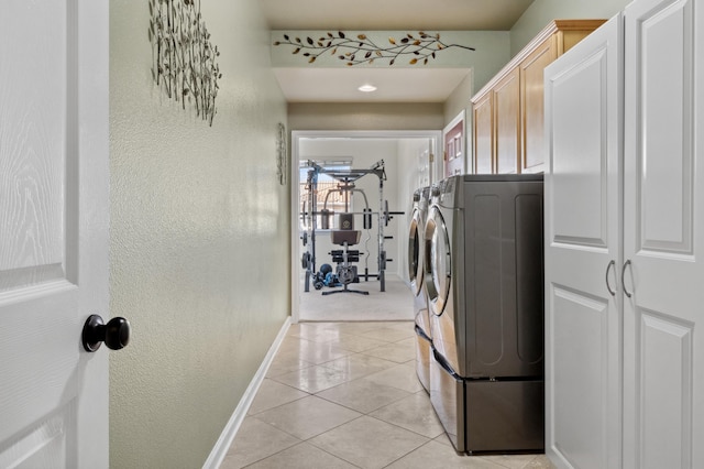 washroom with baseboards, light tile patterned flooring, cabinet space, a textured wall, and independent washer and dryer