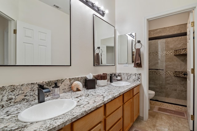 bathroom with double vanity, tiled shower, and a sink