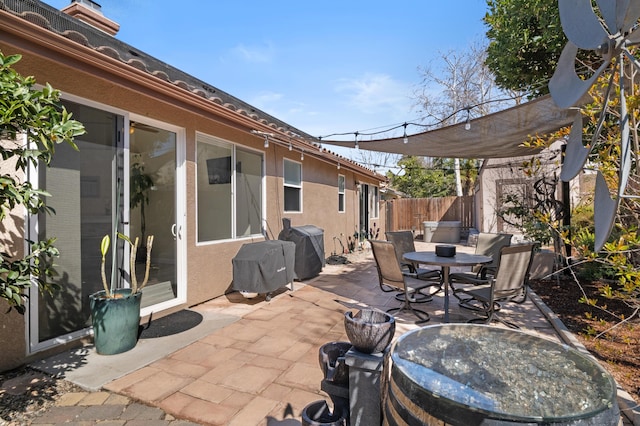 view of patio / terrace featuring outdoor dining space, fence, and a hot tub