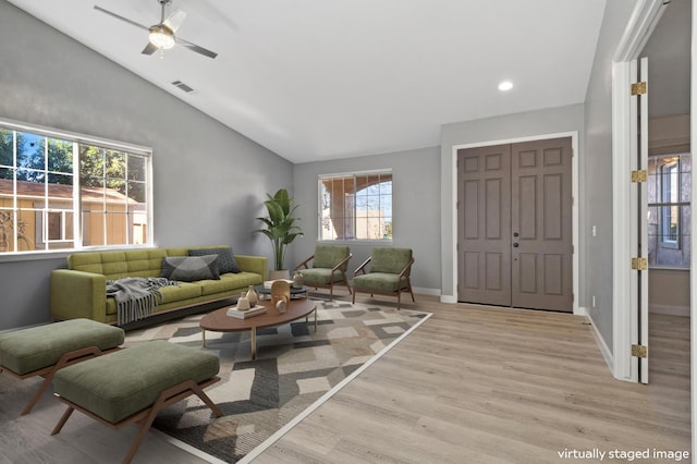 living room featuring light wood finished floors, visible vents, ceiling fan, baseboards, and vaulted ceiling