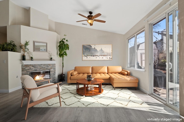 living area featuring wood finished floors, visible vents, baseboards, lofted ceiling, and a fireplace