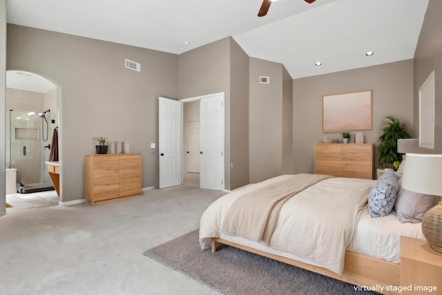 bedroom featuring light carpet, visible vents, ensuite bathroom, and lofted ceiling