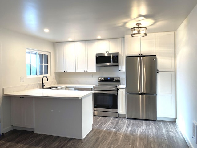 kitchen with stainless steel appliances, white cabinetry, kitchen peninsula, and sink