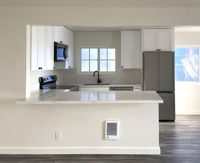 kitchen with appliances with stainless steel finishes, a healthy amount of sunlight, kitchen peninsula, and white cabinetry