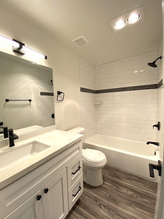 full bathroom featuring tiled shower / bath, hardwood / wood-style flooring, vanity, and toilet