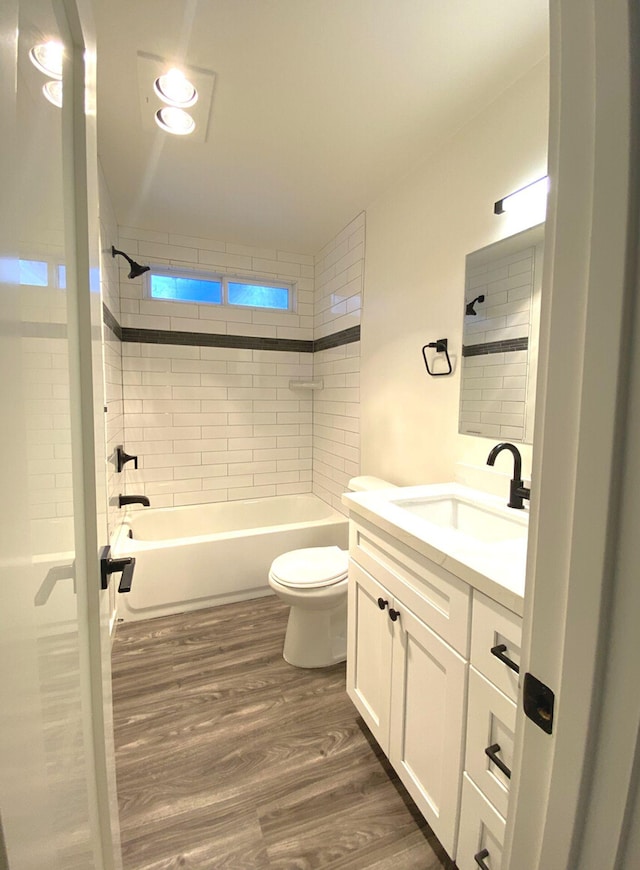 full bathroom featuring tiled shower / bath, vanity, toilet, and hardwood / wood-style flooring