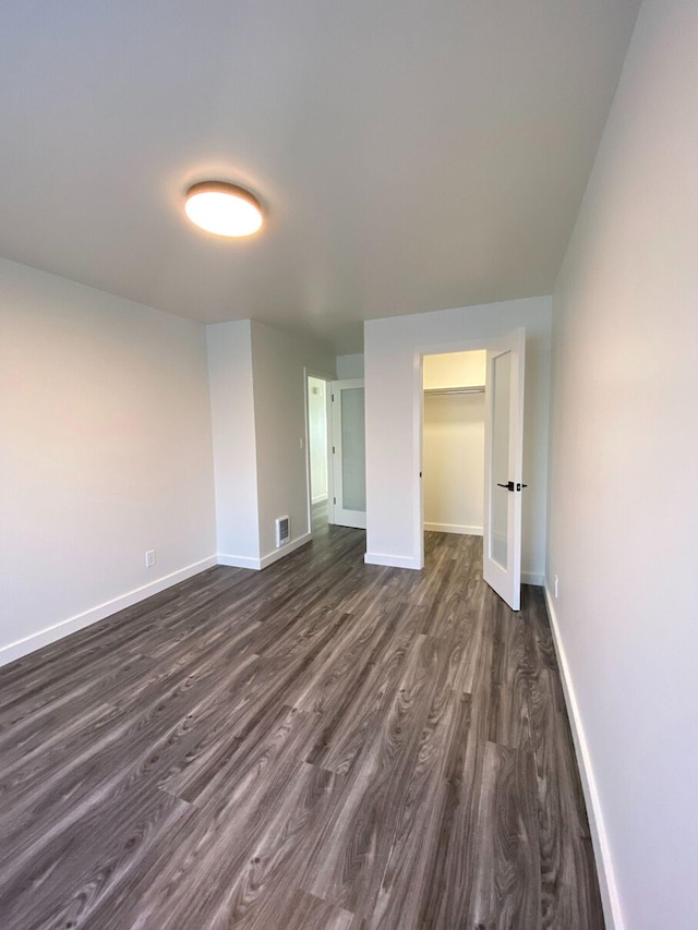 unfurnished bedroom with dark hardwood / wood-style flooring, a walk in closet, and a closet