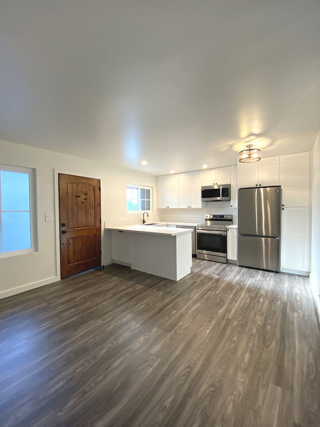 kitchen featuring dark hardwood / wood-style floors, sink, white cabinetry, kitchen peninsula, and stainless steel appliances