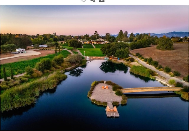 aerial view at dusk featuring a water view