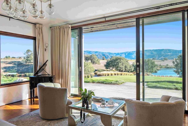 living area featuring a wealth of natural light, a water and mountain view, and hardwood / wood-style flooring