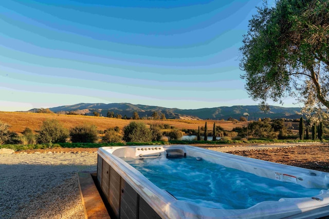 view of swimming pool featuring a mountain view, a rural view, and a hot tub