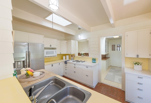 kitchen with white appliances, sink, hanging light fixtures, white cabinetry, and beamed ceiling