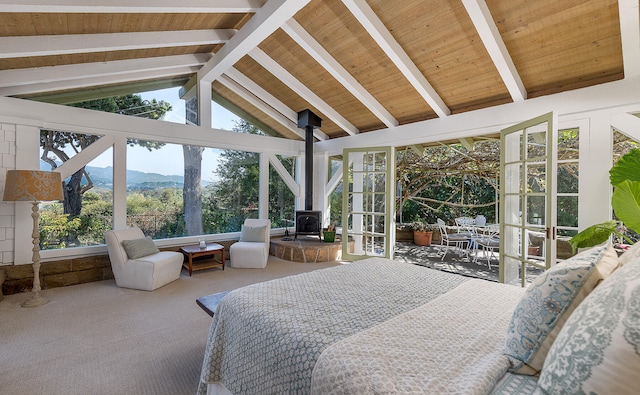 carpeted bedroom with beamed ceiling, a mountain view, a wood stove, wooden ceiling, and high vaulted ceiling