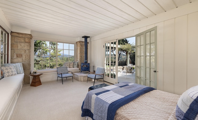 carpeted bedroom with french doors, a wood stove, and wooden ceiling