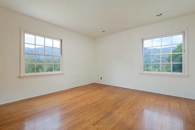 empty room featuring a mountain view and hardwood / wood-style floors