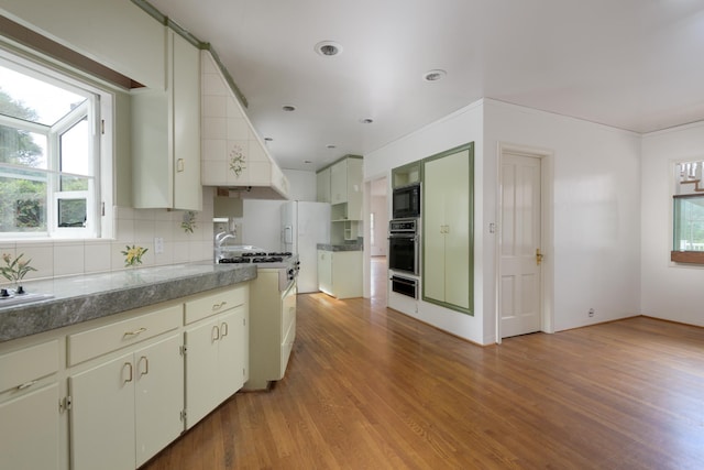 kitchen featuring backsplash, black appliances, plenty of natural light, and light wood-type flooring