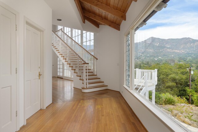 interior space featuring a mountain view, lofted ceiling with beams, wooden ceiling, and light hardwood / wood-style floors