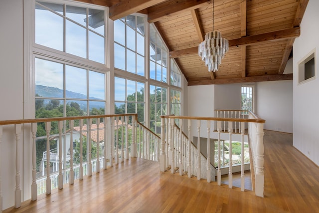 hallway with a mountain view, beamed ceiling, wood-type flooring, and a wealth of natural light