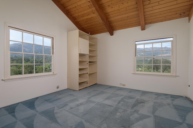 unfurnished bedroom with a mountain view, lofted ceiling with beams, multiple windows, and carpet floors