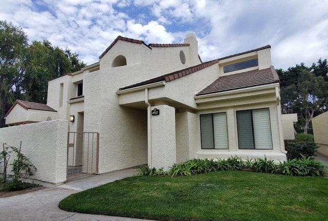 mediterranean / spanish home with a tile roof, a front lawn, and stucco siding