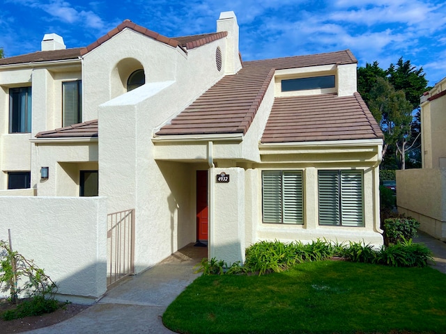 view of front facade with a chimney, a tile roof, and stucco siding