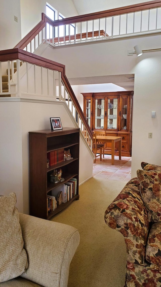 tiled living room with carpet floors, stairs, and a towering ceiling