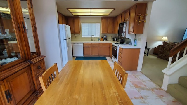 kitchen with light colored carpet, sink, and white appliances