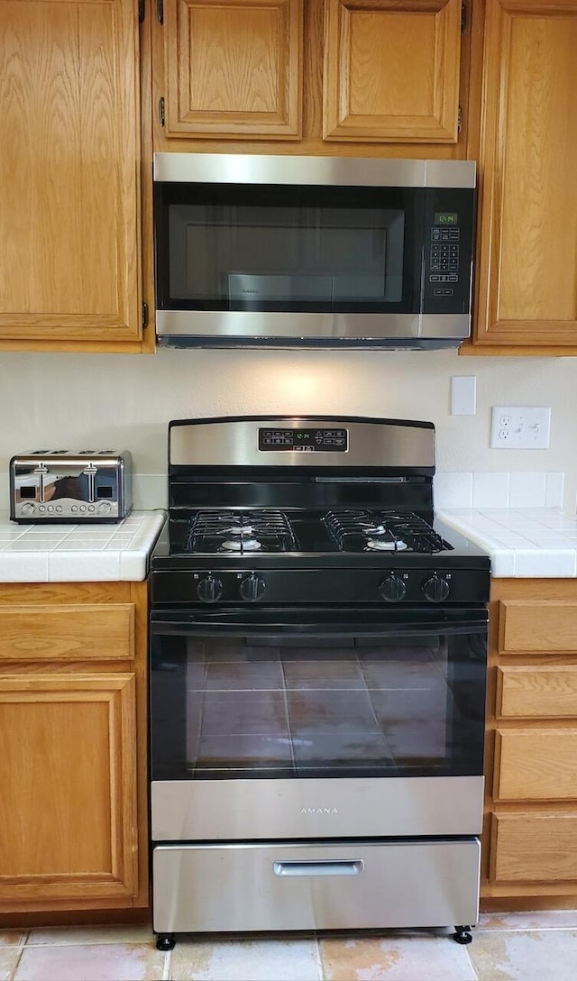 kitchen featuring appliances with stainless steel finishes, a toaster, and tile countertops