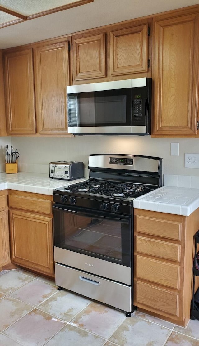 kitchen with a toaster, appliances with stainless steel finishes, and tile counters