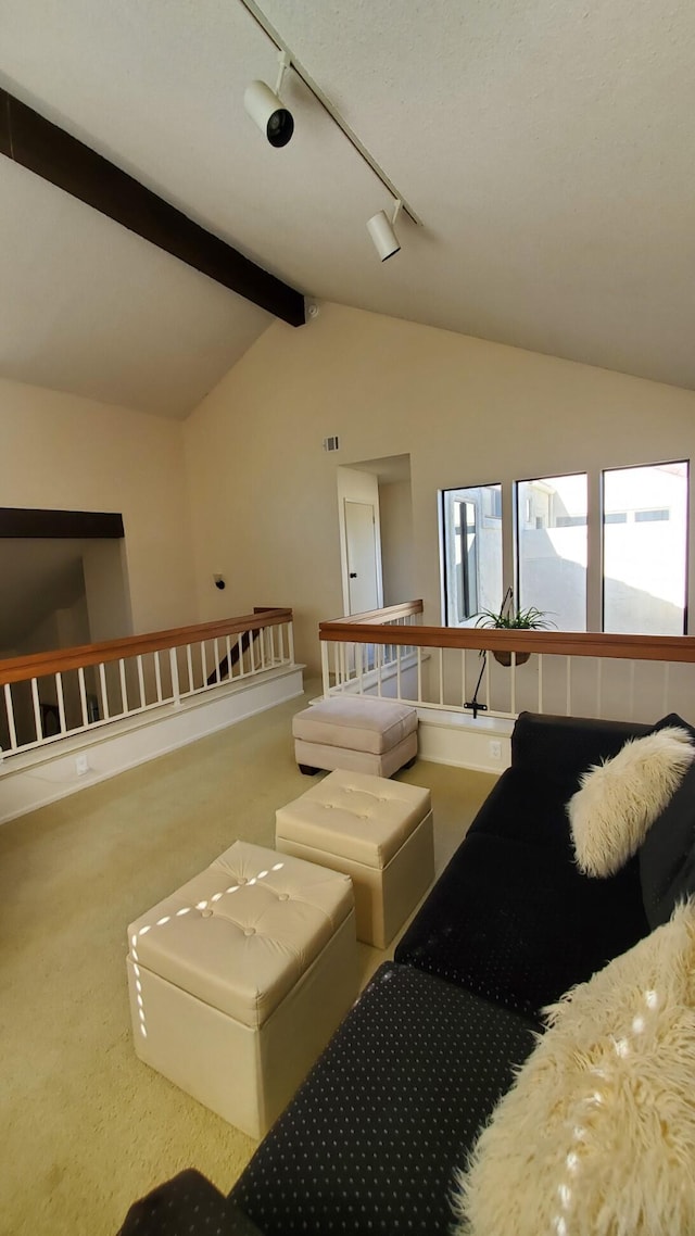 carpeted living area featuring vaulted ceiling with beams and track lighting