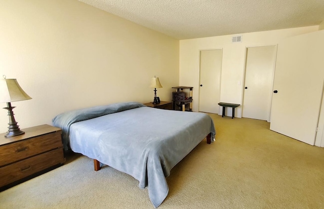 bedroom with a textured ceiling, carpet flooring, and visible vents