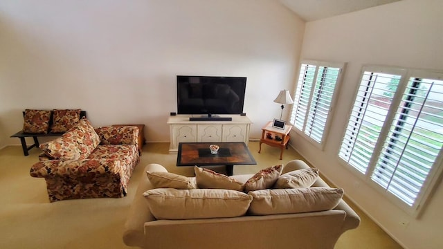 living area with carpet flooring, vaulted ceiling, and baseboards