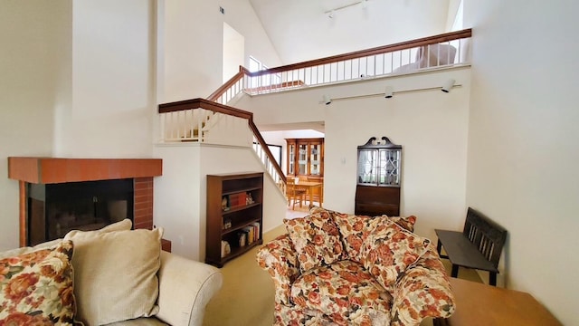 living area featuring stairs, a high ceiling, a fireplace, and carpet flooring