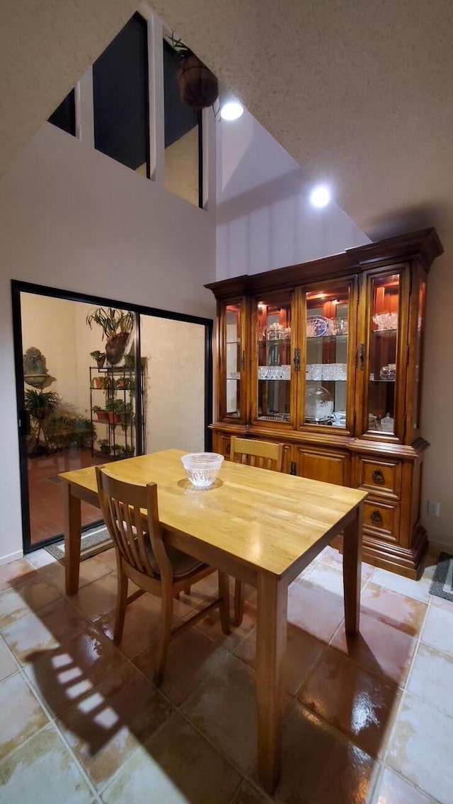 dining room with light tile patterned floors and a high ceiling