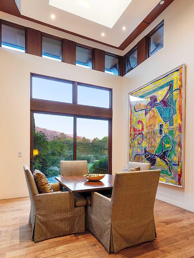 dining space featuring light hardwood / wood-style flooring, a high ceiling, and a wealth of natural light