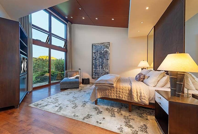 bedroom with access to outside, a high ceiling, and hardwood / wood-style flooring