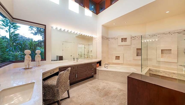 bathroom with a towering ceiling, vanity, and independent shower and bath