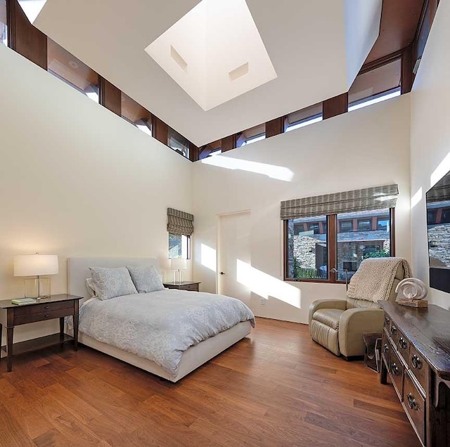 bedroom with wood-type flooring and a towering ceiling