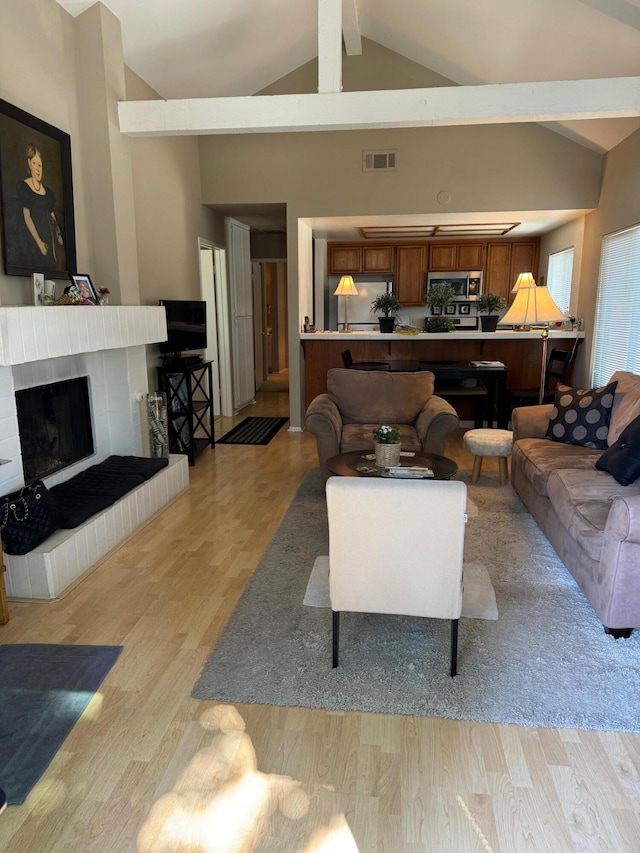 living room with beam ceiling, high vaulted ceiling, and light wood-type flooring