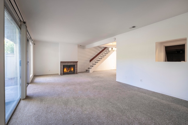 unfurnished living room featuring a tiled fireplace and carpet flooring