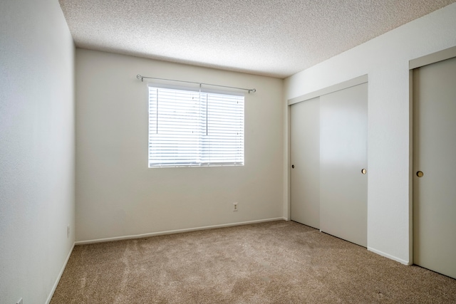 unfurnished bedroom with a textured ceiling and light carpet