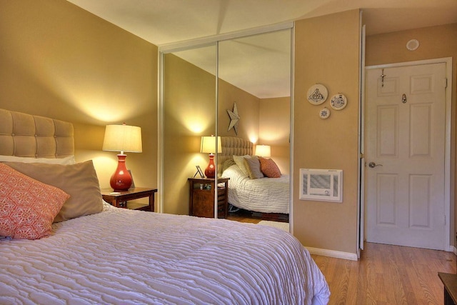 bedroom featuring light wood-type flooring, vaulted ceiling, and a closet