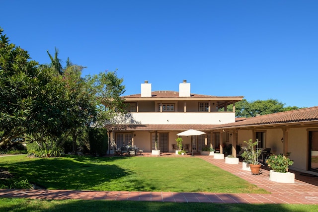 back of house with a lawn and a patio area