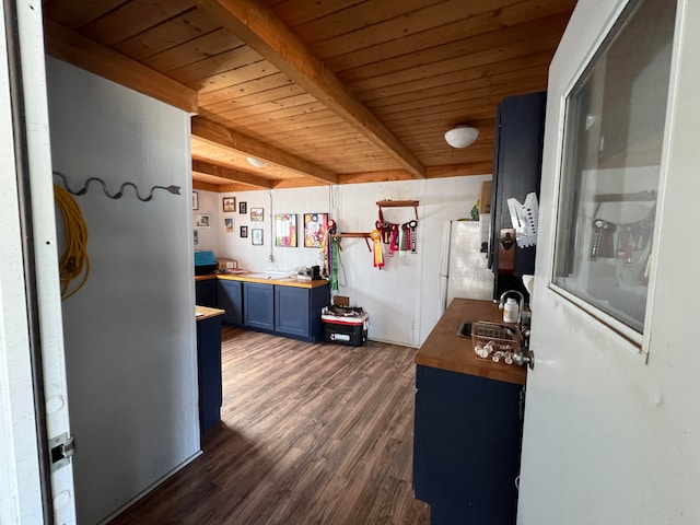 kitchen featuring beamed ceiling, blue cabinets, dark hardwood / wood-style flooring, sink, and butcher block countertops