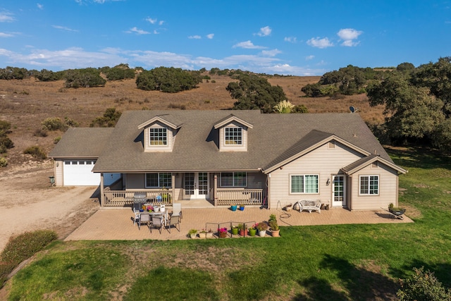 rear view of house featuring a yard, a patio, and a garage