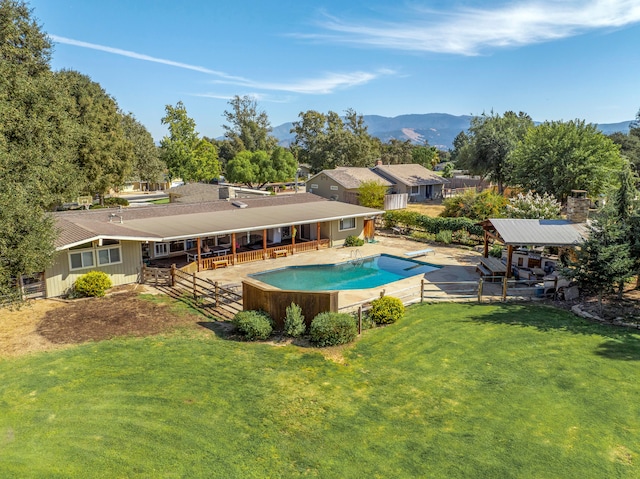 view of swimming pool featuring a patio area, a mountain view, a diving board, and a lawn