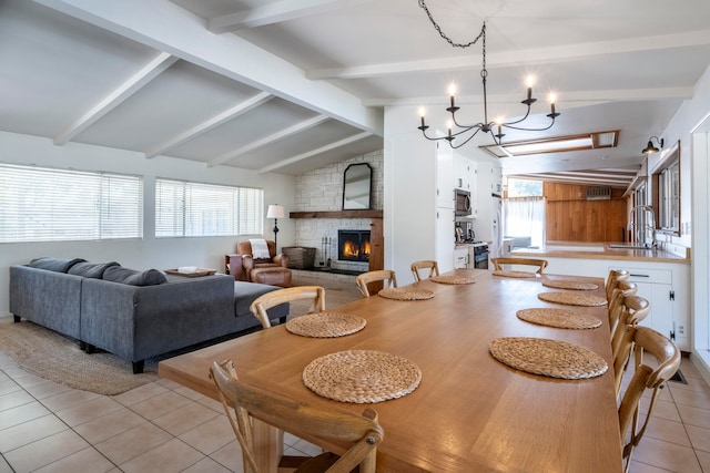 dining room featuring a wealth of natural light, sink, vaulted ceiling with beams, and a fireplace